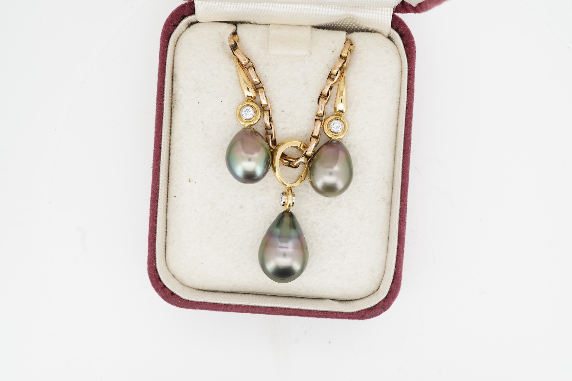 A cultured pearl and diamond demi-parure, comprising: a pendant, suspending a drop-shaped cultured pearl of black tint, measuring approximately 15 x 10.5 x 10.5mm, surmounted by a collet-set brilliant-cut diamond weighin